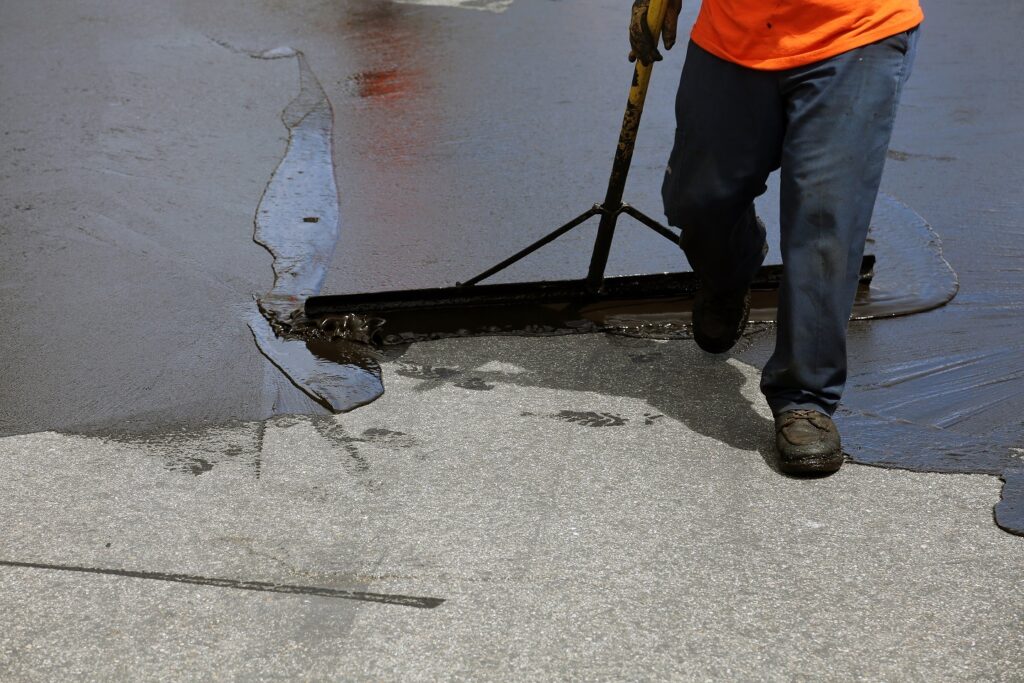 worker applying asphalt sealant